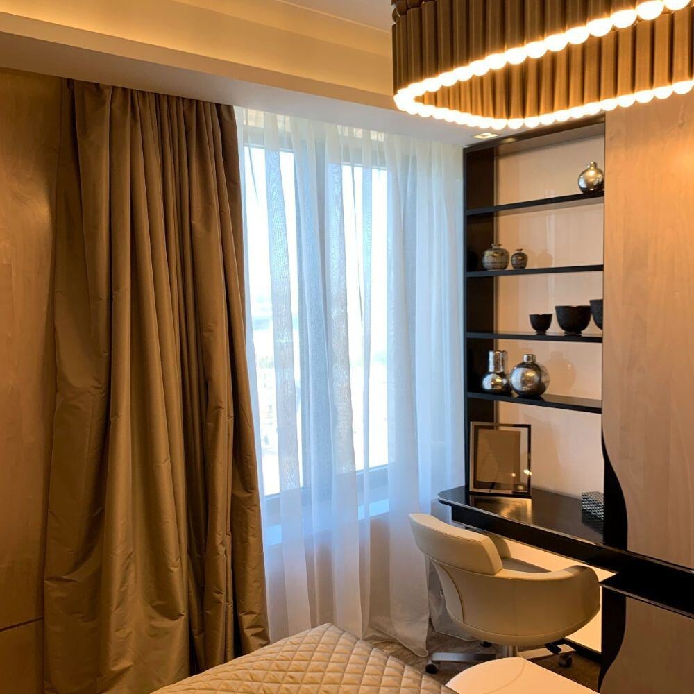 Refined bedroom workspace with custom shelving and luxurious curtains.
