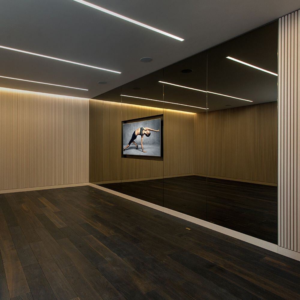 Private luxury gym with mirror wall and slatted timber detailing in a high-end Belgravia residence.