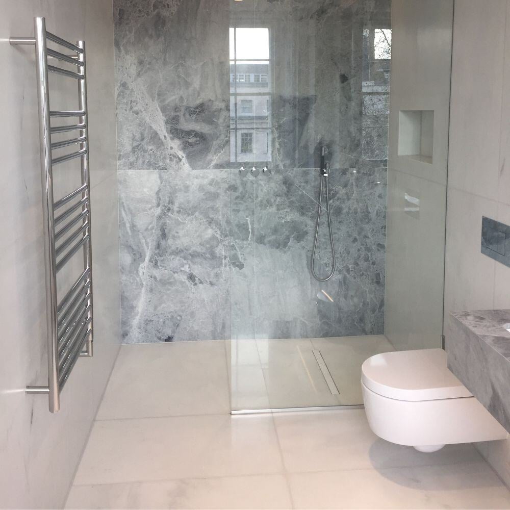 Contemporary walk-in shower with grey marble feature wall and floating toilet in a high-end Belgravia bathroom.