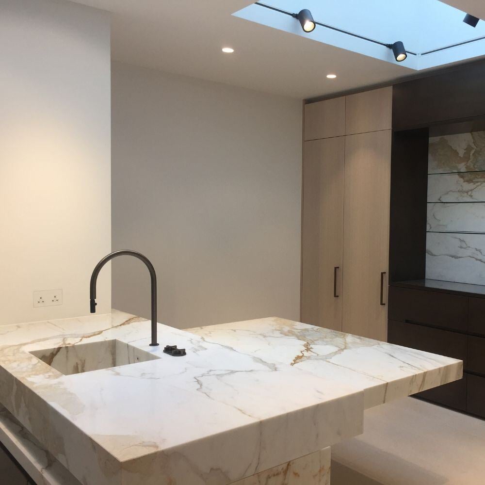 Bespoke marble kitchen island with integrated sink and luxury built-in appliances in Belgravia home.