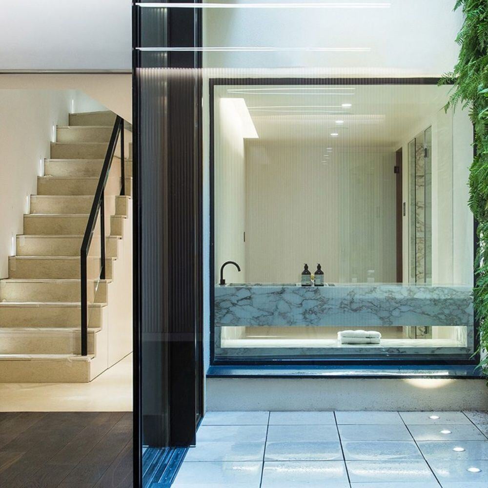 Outdoor wellness courtyard with marble sink and vertical green wall, part of a Belgravia refurbishment project.