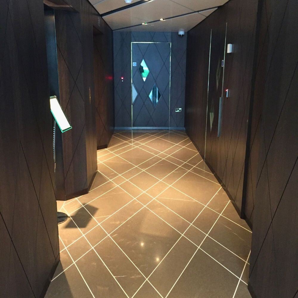 Dark-toned main corridor of Chelsea Waterfront featuring angular walls and tiled flooring.