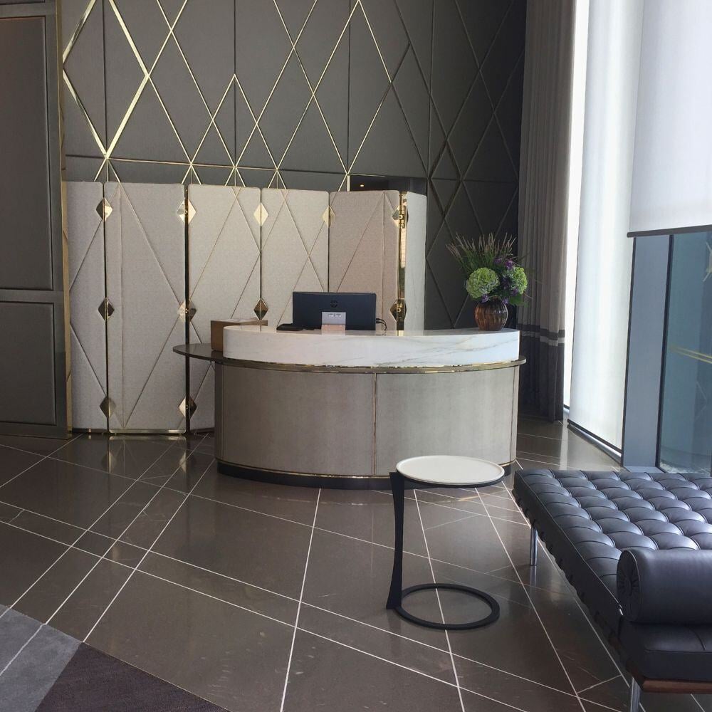 Reception desk area in Chelsea Waterfront with upholstered backdrop and marble counter.