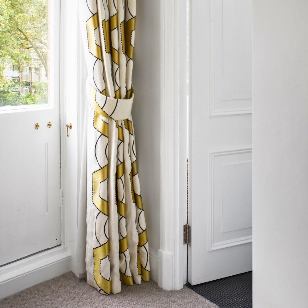 Curtain detail beside white door and sash window in London apartment bedroom renovation.