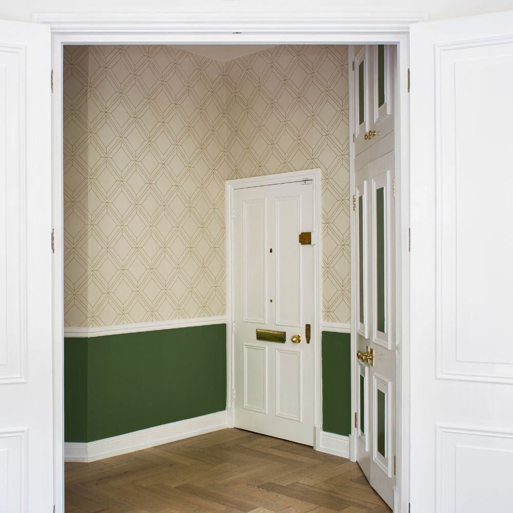 Refurbished London hallway with green half-wall panelling, decorative wallpaper, and natural wood floor.