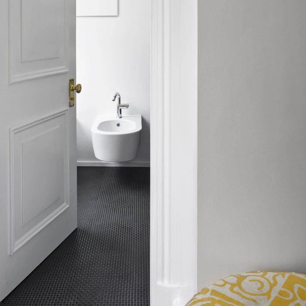 Compact bidet room with wall-mounted sanitaryware and black micro-tiled flooring in London home.