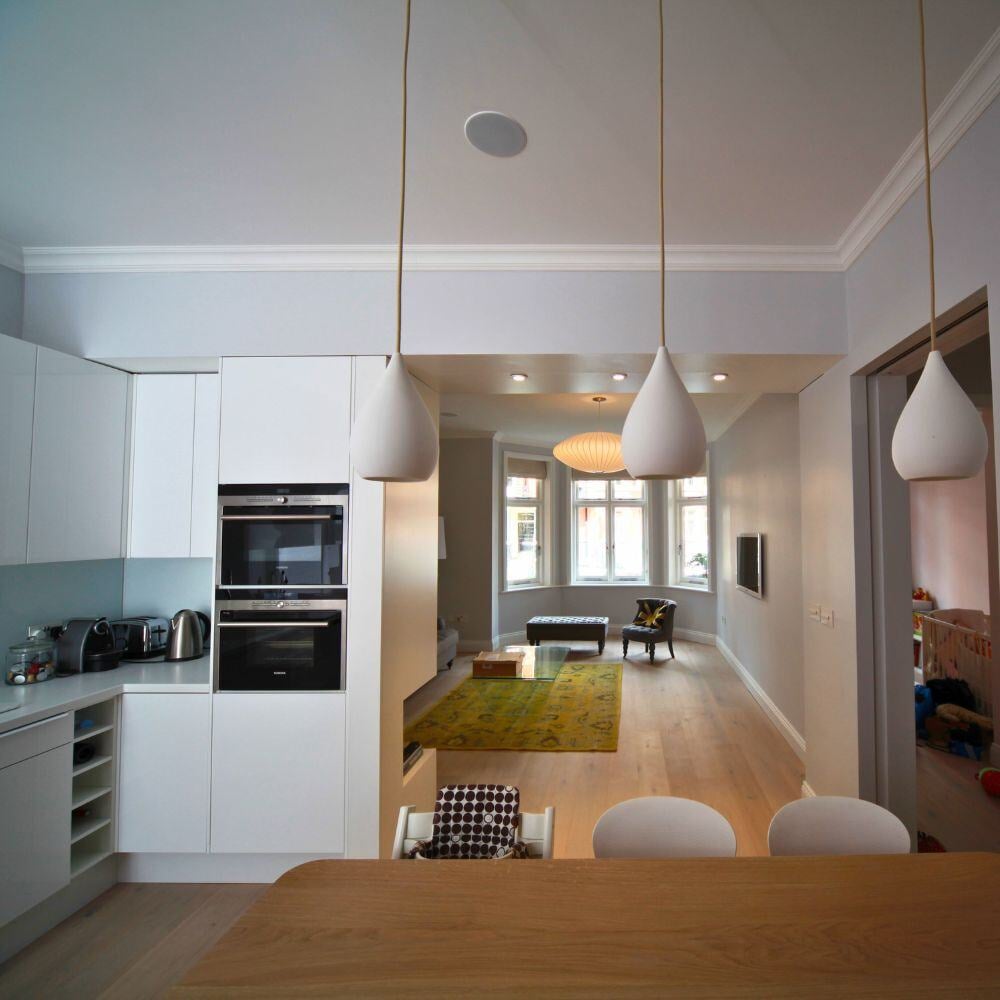 View from kitchen dining area into living room featuring pendant lights and bay windows.