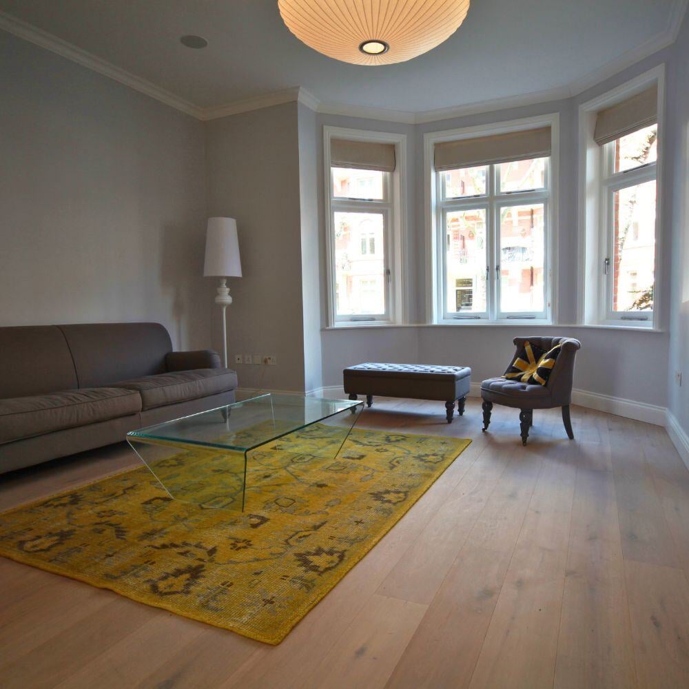 Spacious living room with bay window, neutral tones, and elegant furnishings.