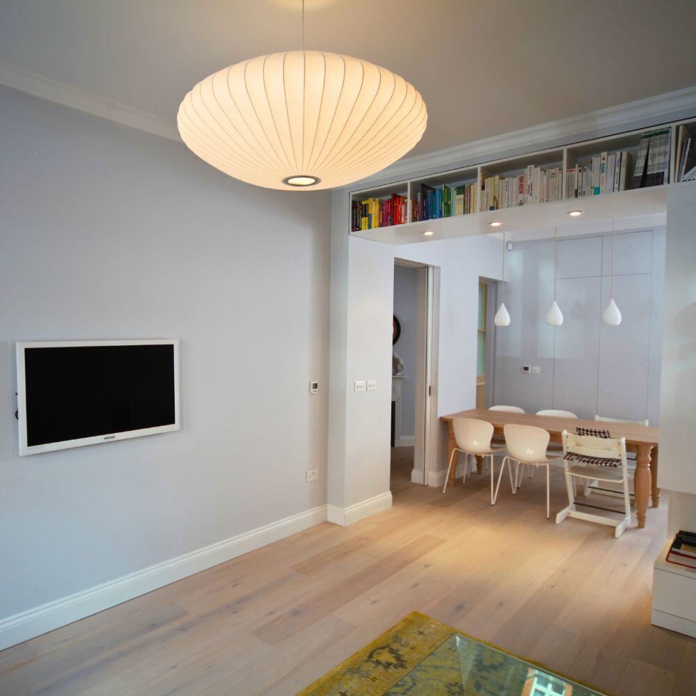 Wall-mounted TV in a soft grey living room with light wooden flooring and warm lighting