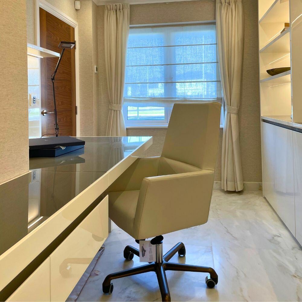Home office with sleek white furniture, neutral decor, and full-height curtains over marble flooring.
