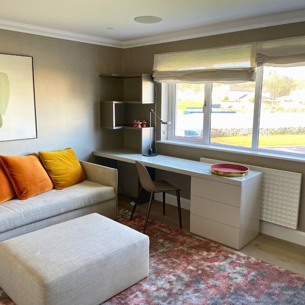 Guest bedroom featuring soft-toned furnishing, large window, and functional work desk.