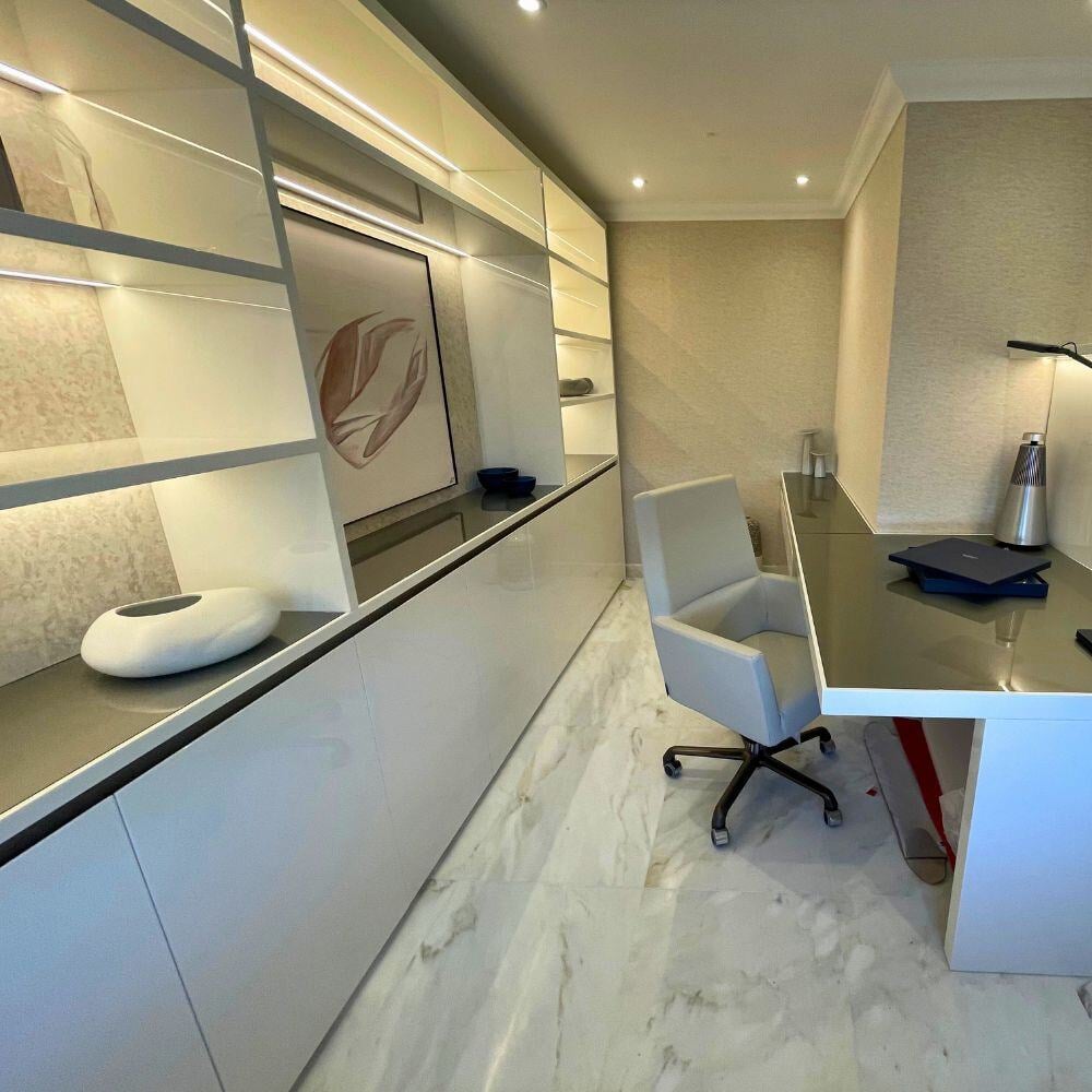 Bespoke home office with custom shelving, integrated lighting, and marble-effect flooring.