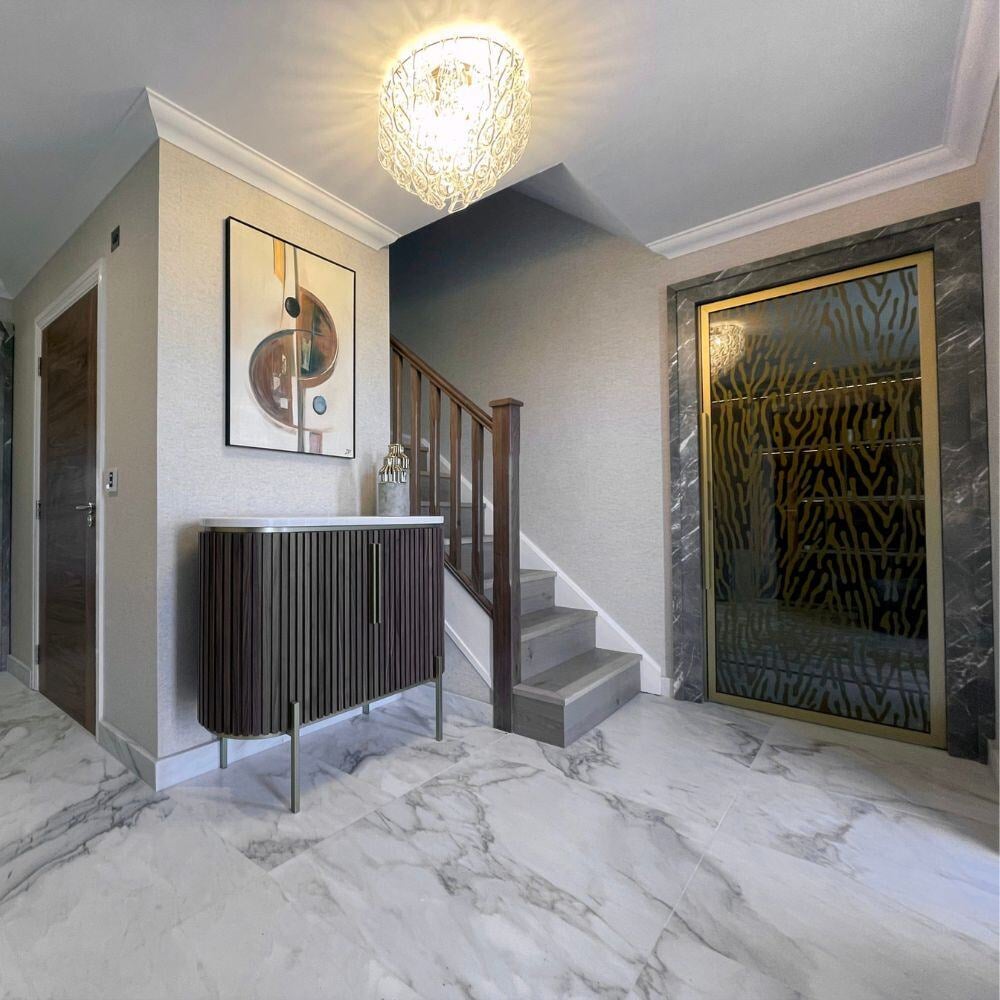 Statement hallway with crystal chandelier, marble tiles, and bronze-framed decorative glass doors.