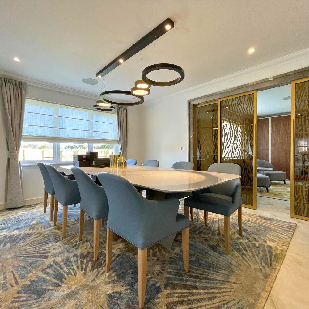 Refined dining area with gold sliding doors, navy dining chairs, and a light-toned marble floor.