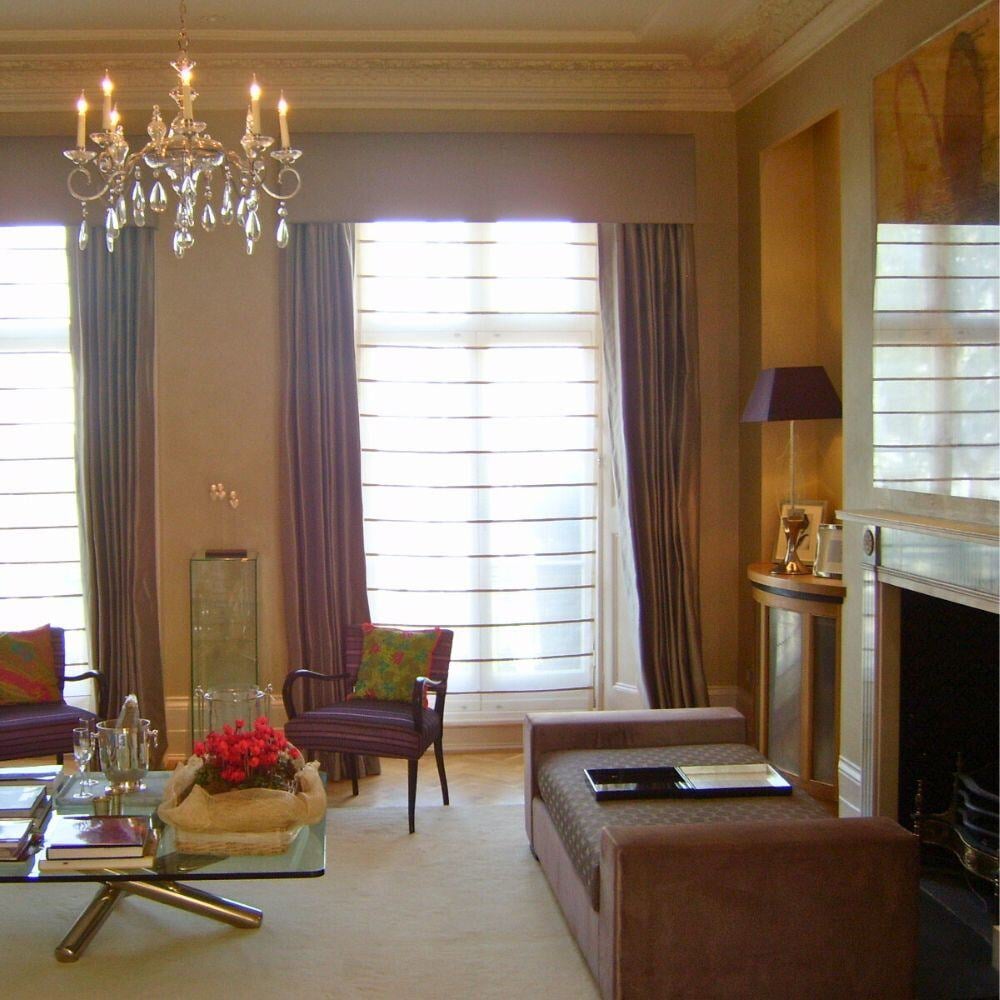 Grand living space with full-height windows, chandelier, and rich drapery.