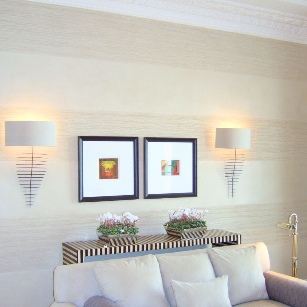 Soft-toned living room wall with sculptural wall lamps and framed modern art.