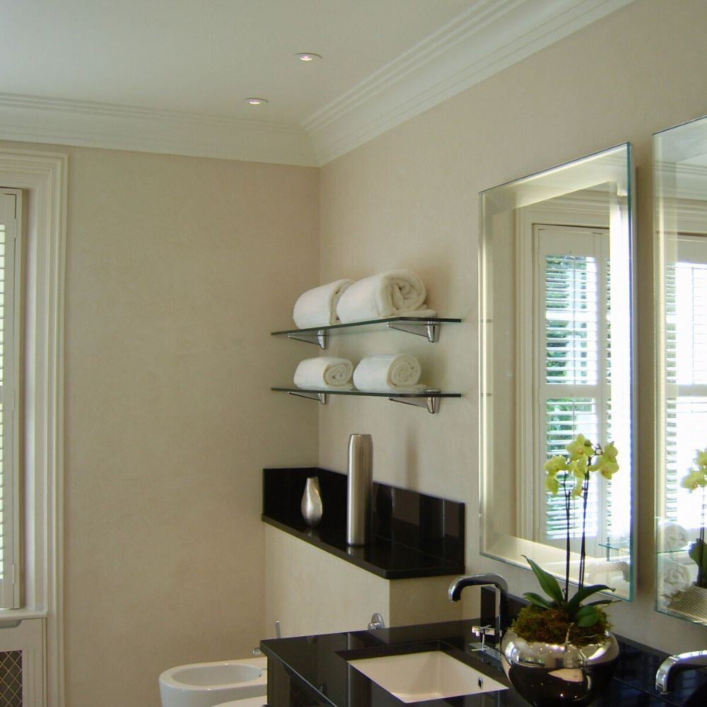 Contemporary bathroom featuring black vanity, glass shelves, and soft cream walls.