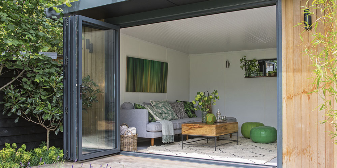 Modern garden room with open bi-fold doors and natural wood cladding, part of a luxury home renovation in London.
